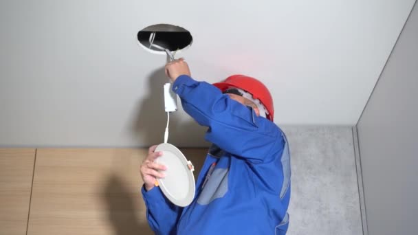 Electricista con casco rojo comprobando la iluminación del panel led en casa
 - Metraje, vídeo