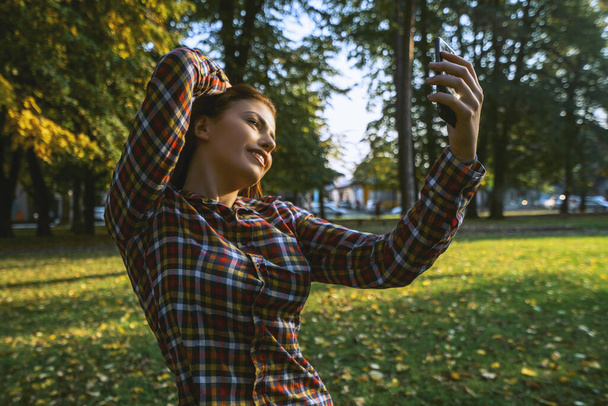 Selfie time. Beautiful young girl taking a selfie at the park. - Fotografie, Obrázek