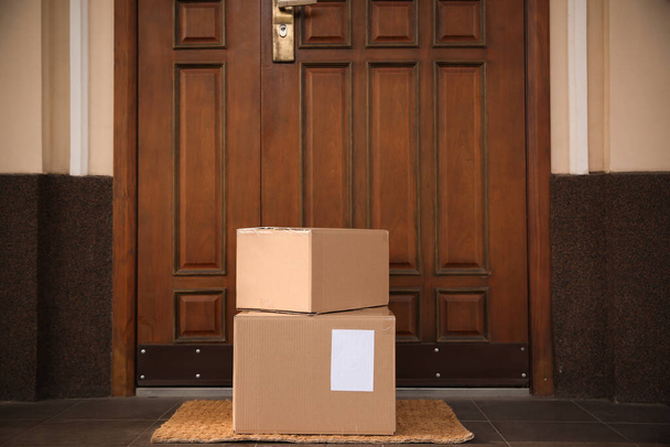 Delivered parcels on door mat near entrance - Φωτογραφία, εικόνα