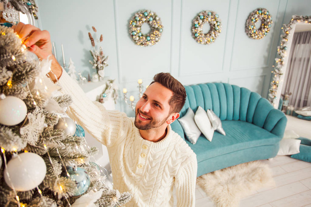 Man decorating fir tree while winter holidays - Photo, image