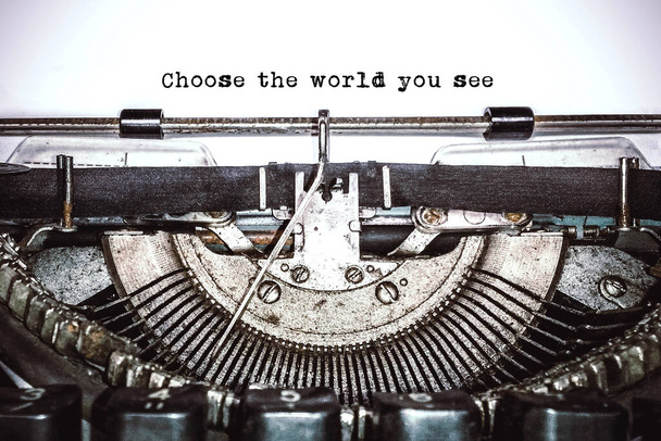 Oude vintage typemachine, retro machine met wit vel papier en getypte tekst "choose the world you see", kopieer ruimte, close up - Foto, afbeelding