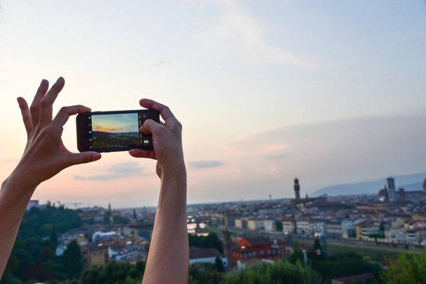 Closeup of a womaen hand with smartphone taking a panaramic picture of Florence, Italy - Fotó, kép