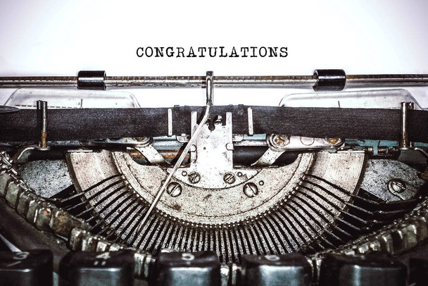 Old vintage typewriter, retro machine with white sheet of paper and typed text "congratulations", copy space, close up - Fotoğraf, Görsel