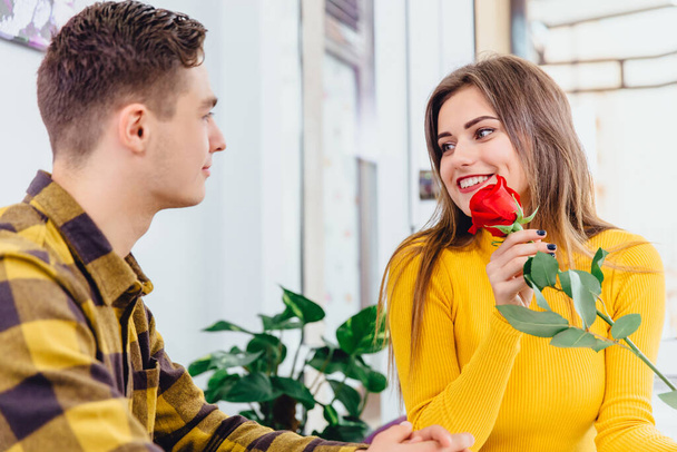Appreciation concept. Beautiful smiling woman with red rose in her hand is really grateful to her beloved man for such a present. - Foto, Imagem