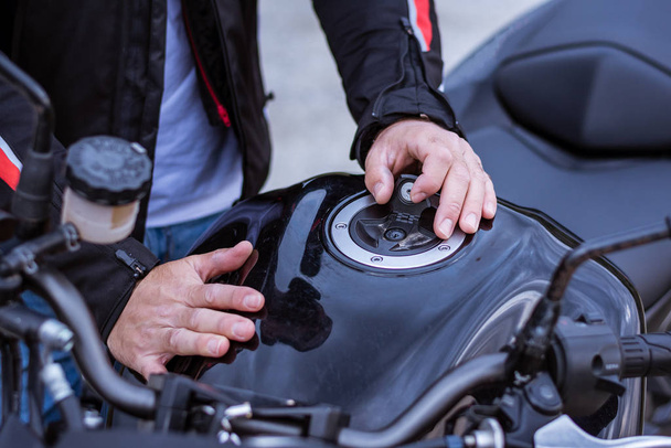 Biker removing the gas cap from his motorcycle. - 写真・画像