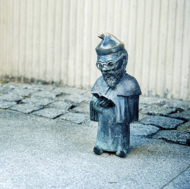 Lectura de enano en toga, profesores sombrero y gafas en Wroclaw, Polonia. Una de las famosas esculturas de enanos en Wroclaw, Breslau en el pasado, símbolos de la ciudad polaca. Destino de viaje. Atracción turística
 - Foto, Imagen