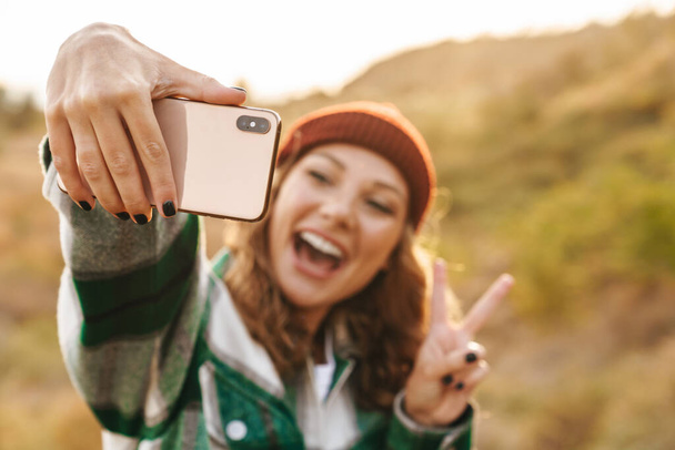 Image of woman taking selfie photo on cellphone while walking ou - Foto, Imagem