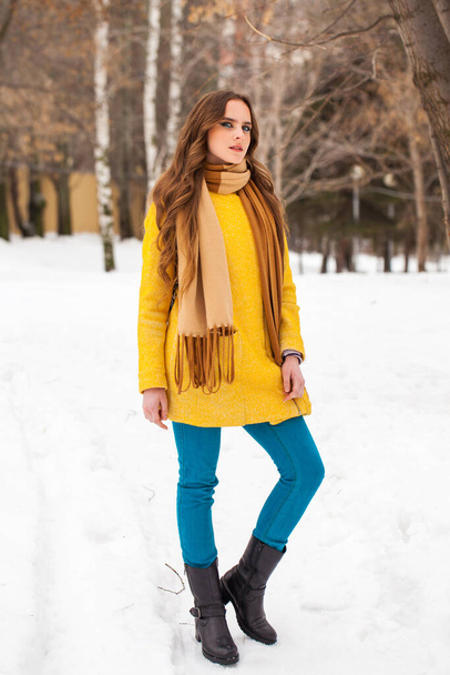 Young beautiful woman in yellow coat walking winter park - Foto, Imagen