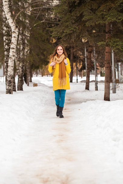 Young beautiful woman in yellow coat walking winter park - Fotoğraf, Görsel