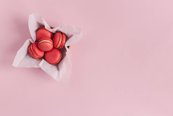 Rode franse macarons in een doos op een roze achtergrond. Concept voor Valentijnsdag.  - Foto, afbeelding