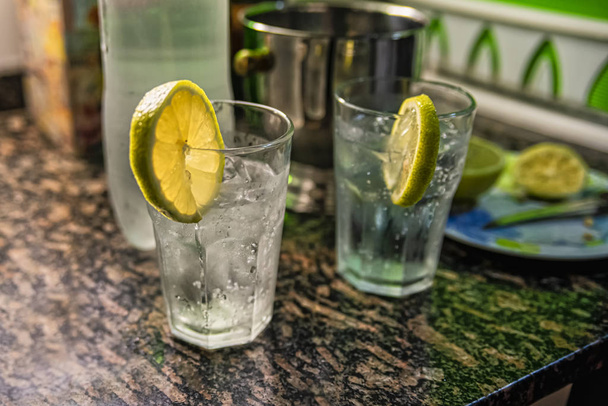 Bevanda alcolica fatta in casa (tonic cocktail tonic) con limone e ghiaccio sul tavolo di marmo
. - Foto, immagini