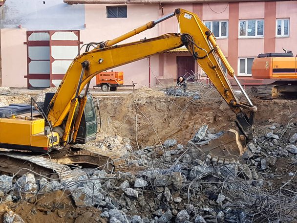 Construction work - dismantling. Professional demolition of reinforced concrete structures using industrial hydraulic hammer. Rods of metal fittings. Wreckage and crumbles of concrete. - Photo, Image