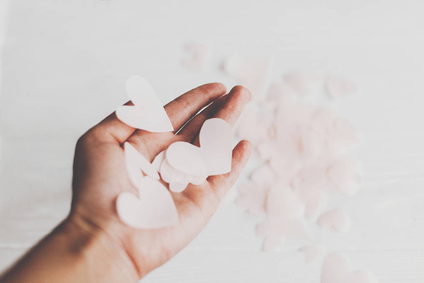 Χέρι κρατώντας χαριτωμένο ροζ παστέλ καρδιές σε λευκό φόντο με s - Φωτογραφία, εικόνα