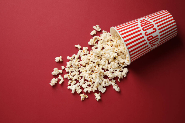 Delicious popcorn on red background, above view - Φωτογραφία, εικόνα