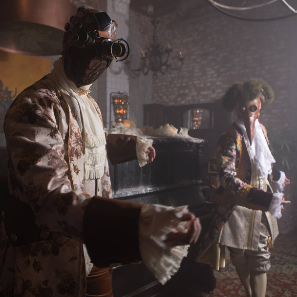 Actors in Steam punk masks and antique costumes indoor. - Фото, изображение