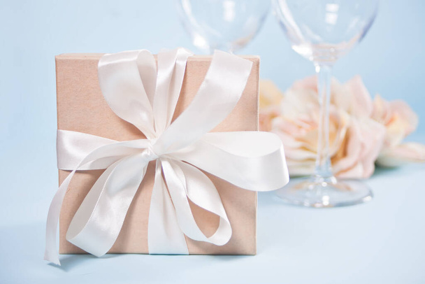 Gift box with empty two wineglasses and flowers on the background. Romantic dinner concept. - 写真・画像