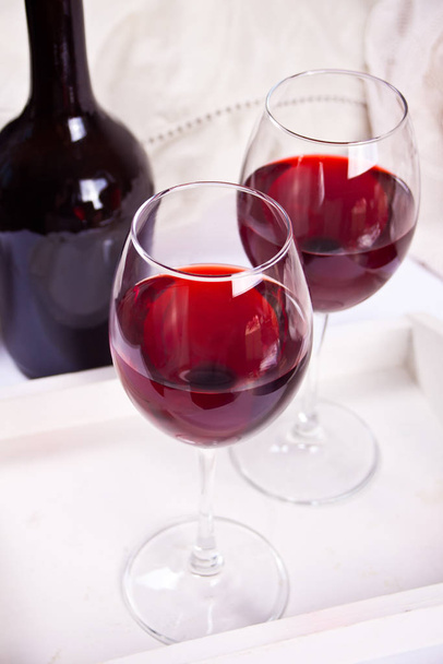 Two glasses with red grape wine with bottle on the background. Romantic dinner concept. - Foto, immagini