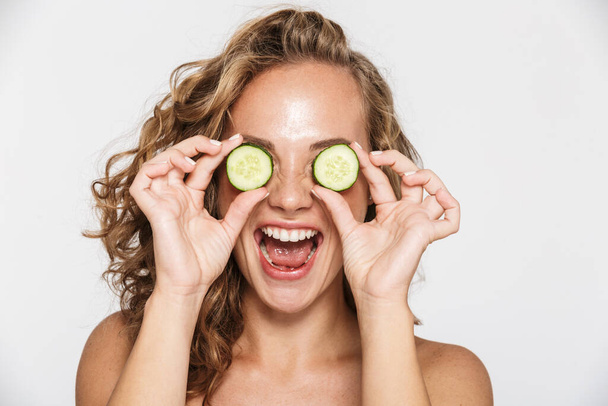 Image of delighted half-naked woman making fun with pieces of cucumber - Foto, Imagem