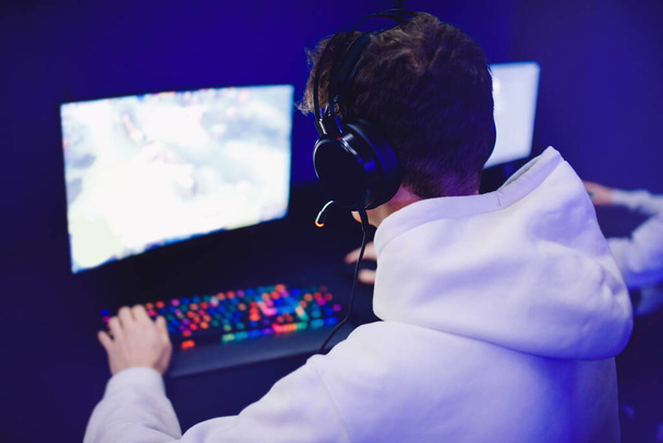 Jugador profesional jugando torneos online videojuegos ordenador con auriculares, rojo y azul - Foto, Imagen
