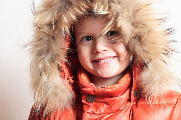 Smiling child in fur hood and orange winter jacket.fashion boy - Fotografie, Obrázek