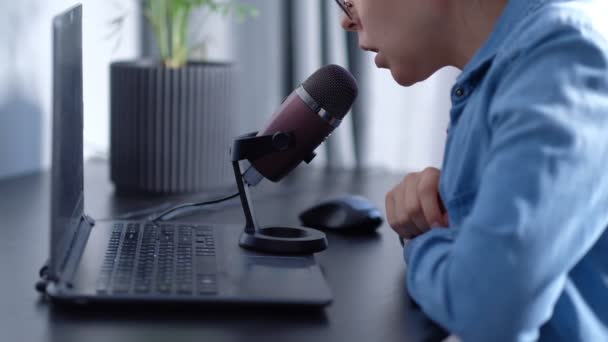 Portret młodej blogerki prowadzącej transmisję na żywo, przemawia do micraphona. kobieta prowadzi podcast w domu przed laptop - Materiał filmowy, wideo