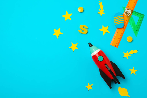 Bright toy rocket and school supplies on light blue background, flat lay. Space for text - 写真・画像