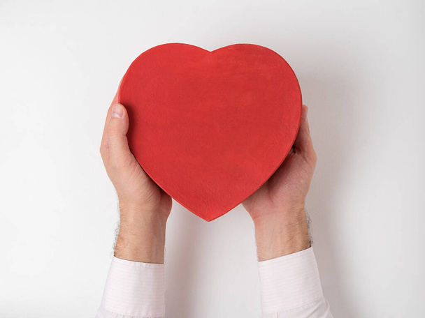 Caja en forma de corazón rojo de estilo vintage en manos masculinas aisladas sobre fondo blanco
 - Foto, imagen