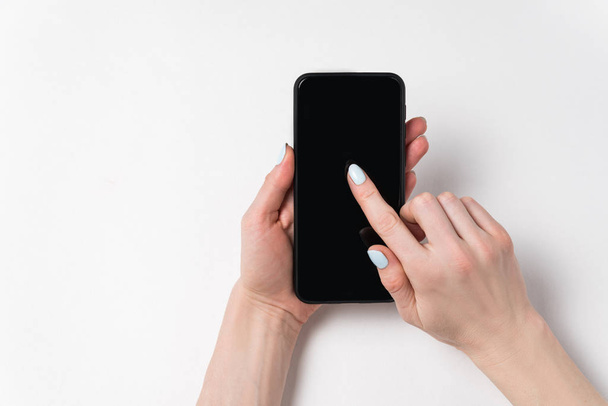 Vrouwelijke handen die telefoon vasthouden en op het scherm laten zien. Zwart display, witte achtergrond, kopieerruimte - Foto, afbeelding