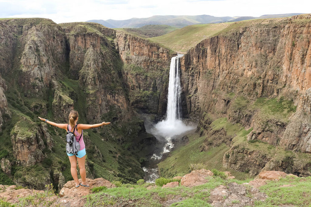 Женщина, стоящая рядом с потрясающим водопадом, бегущая по каньону степа
 - Фото, изображение