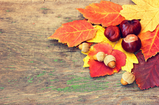 Autumnal leaves and chestnuts on a wooden background - Valokuva, kuva