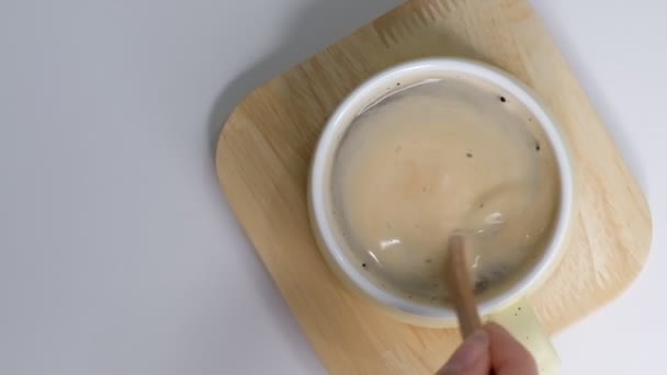 Top view of Person hand steering coffee in a cup with spoon. Breakfast morning of a cup hot black coffee on white background. Closeup Slow motion. - Footage, Video