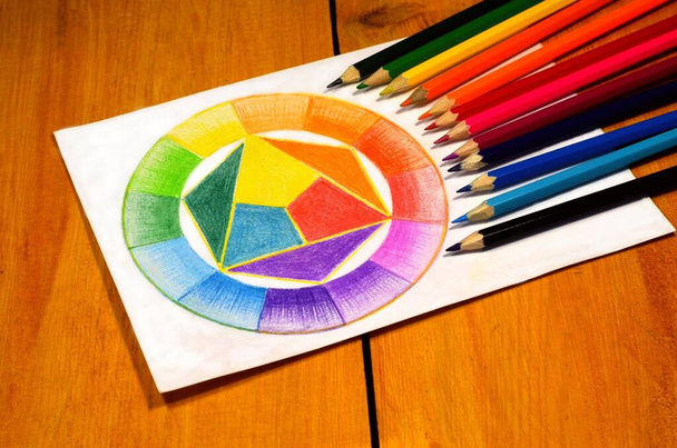 Vidíme barevný kruh nakreslený tužkami. Celkem je tam 12 tužek. Vše je umístěno na dřevěném stole. - Fotografie, Obrázek