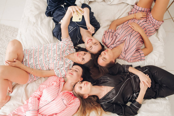 Csinos lányok pizsamában szelfit csinálnak az ágyon.. - Fotó, kép