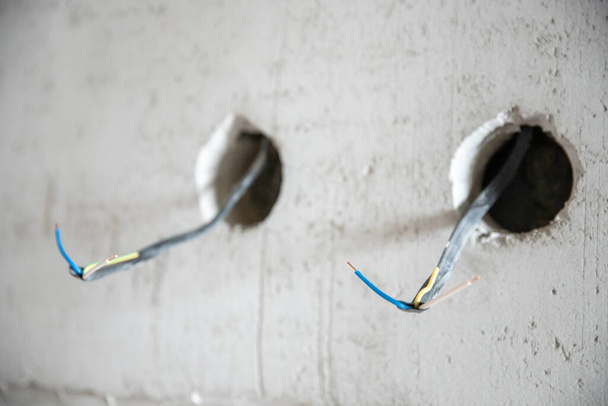 Elektrické práce s hrubým povrchem, elektrikář připojuje a montuje měděné dráty pro zásuvky v bytě - Fotografie, Obrázek