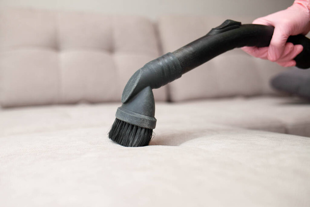 close up of woman's hand cleaning couch using vacuum cleaner at home sofa - Foto, imagen