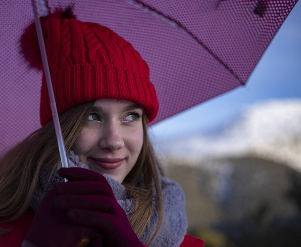 mujer con gorra roja y un paraguas en la nieve
 - Foto, imagen