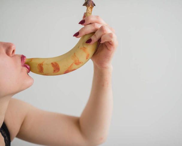 Adult European girl sexually licks and sucks a big banana. Fantasies about oral sex. Face close-up. - Foto, Imagem