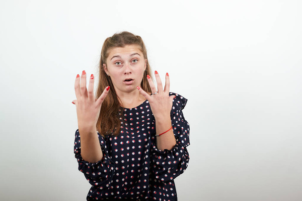 дівчина в сукні з білими колами нервово незадоволена дівчина показує напружені пальці
 - Фото, зображення