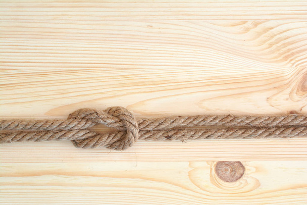 Морской узел, используемый в яхтинге, квадратный узел. Морской узел на деревянном фоне
. - Фото, изображение