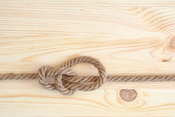 Marine knot used in yachting, bowline knot. Nautical knot on wooden background. - Zdjęcie, obraz