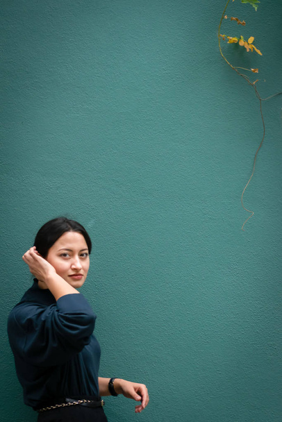 Joven beatifull chica árabe está posando frente a la pared verde con ropa elegante inteligente. Diseño de imagen de fondo con espacio en blanco
. - Foto, imagen