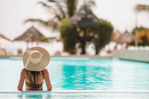 Donna che si rilassa a bordo piscina in un resort di lusso godendo di una vacanza al mare perfetta - Foto, immagini