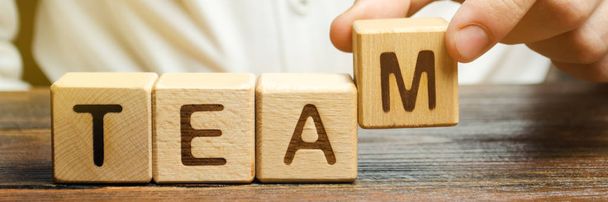 Businessman holds wooden blocks with the word Team. Team management concept. Teamwork. Hiring. Recruitment staff. Work in cooperation. Leadership skills. Analysis and analytics business process - Foto, imagen