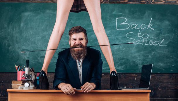 Sexy schoolgirl in plaid skirt and long legs standing at teachers desk. Sexy teacher. Role love game back to school. Anatomy lesson and sex education in high school. - Photo, image