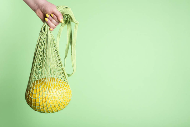 Honeydew melon hanging in mesh shopping bag. Food shopping - 写真・画像