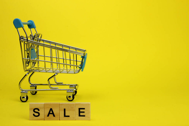 Mini supermarket cart, trolley on a yellow background. Purchases. The Word Sale - Foto, imagen