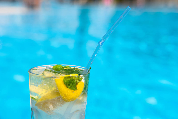 Fresh Mojito Cocktail at the edge of the resorts pool in summer. Luxury vacation concept, a place for text - Фото, зображення