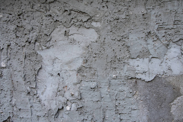 Η υφή ενός τσιμεντένιου τοίχου, άνισα σοβατισμένο, κηλίδες από υγρασία, τραχύτητα και ανωμαλίες. - Φωτογραφία, εικόνα