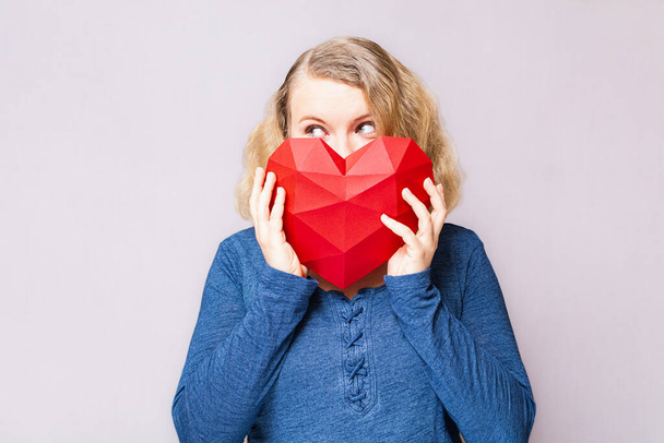 Жінка заглядає з полігонального ромбоподібного червоного серця
 - Фото, зображення