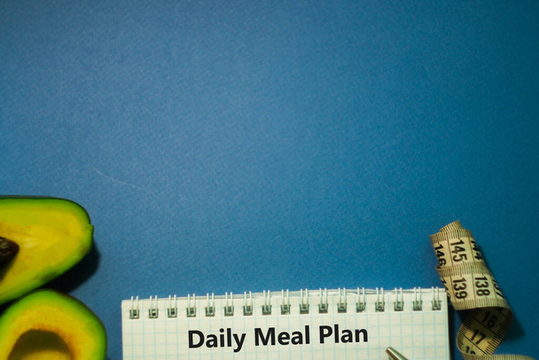 Halved avocado, notepad and measure tape on classic blue background. Nutrition food. Counting calories. Dieting concept. Meal plan - Photo, Image